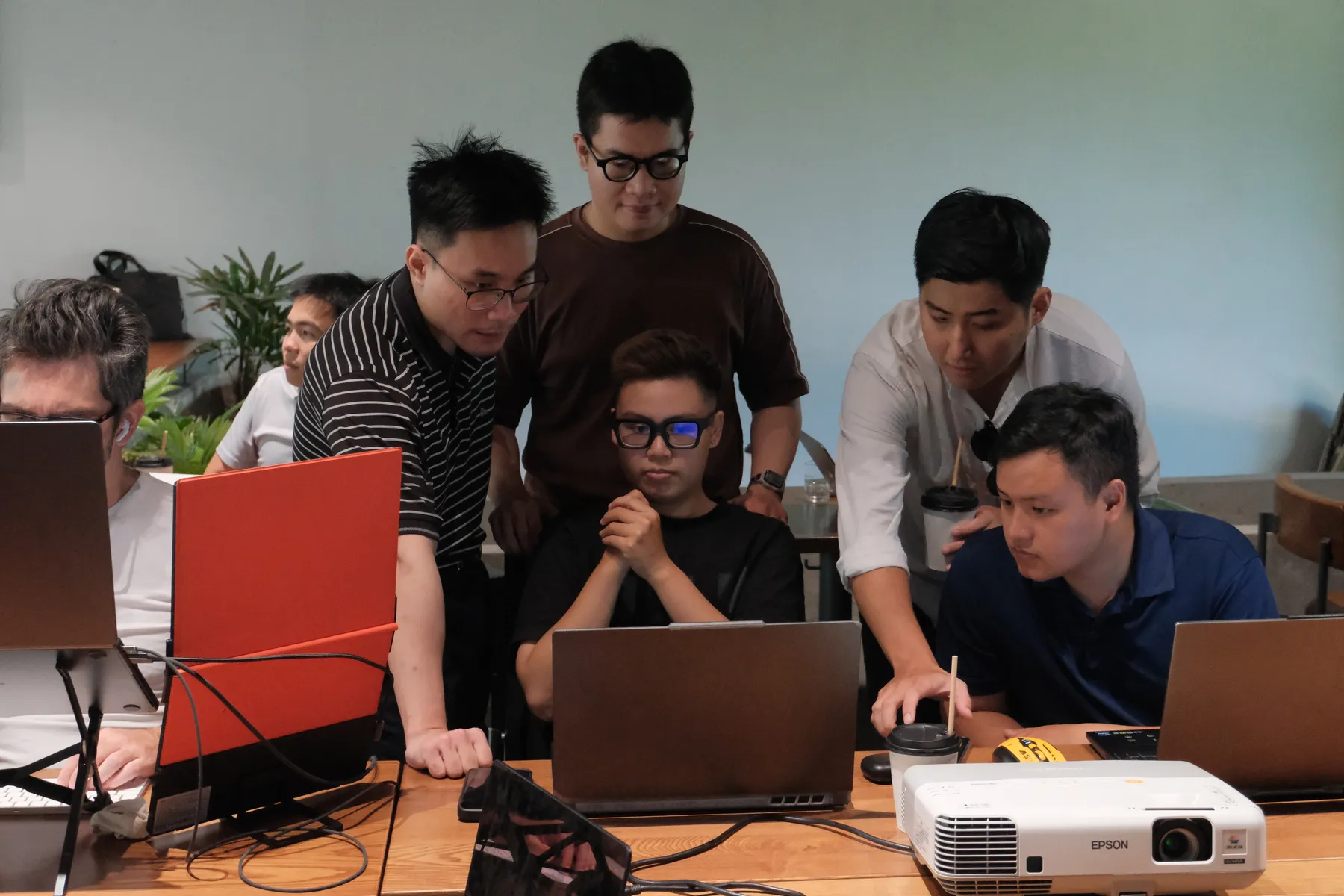Attendees huddled around a laptop at the Frontier Club AI Meetup
